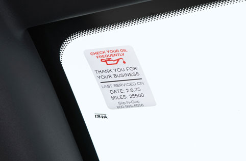 Sticker on car window showing when oil check is next due